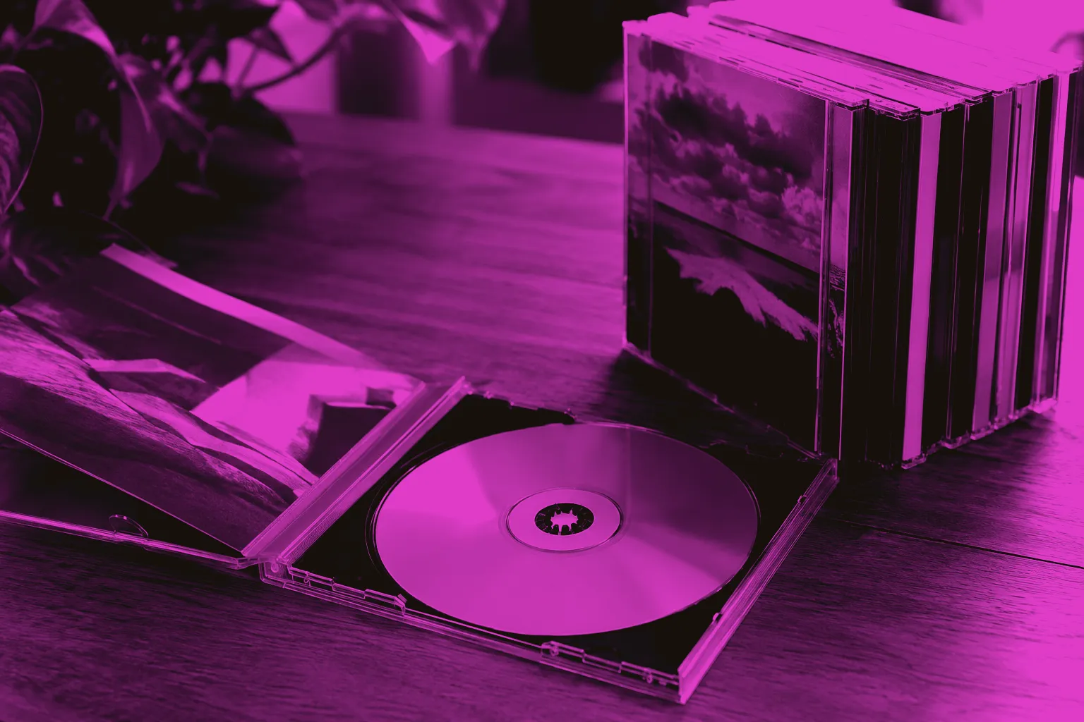 Compact discs, clear jewel cases and an open booklet on a wooden table.