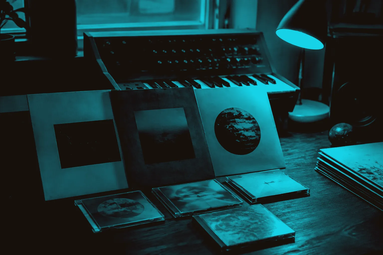 Records and CDs beside a compact synthesizer in a home listening space.
