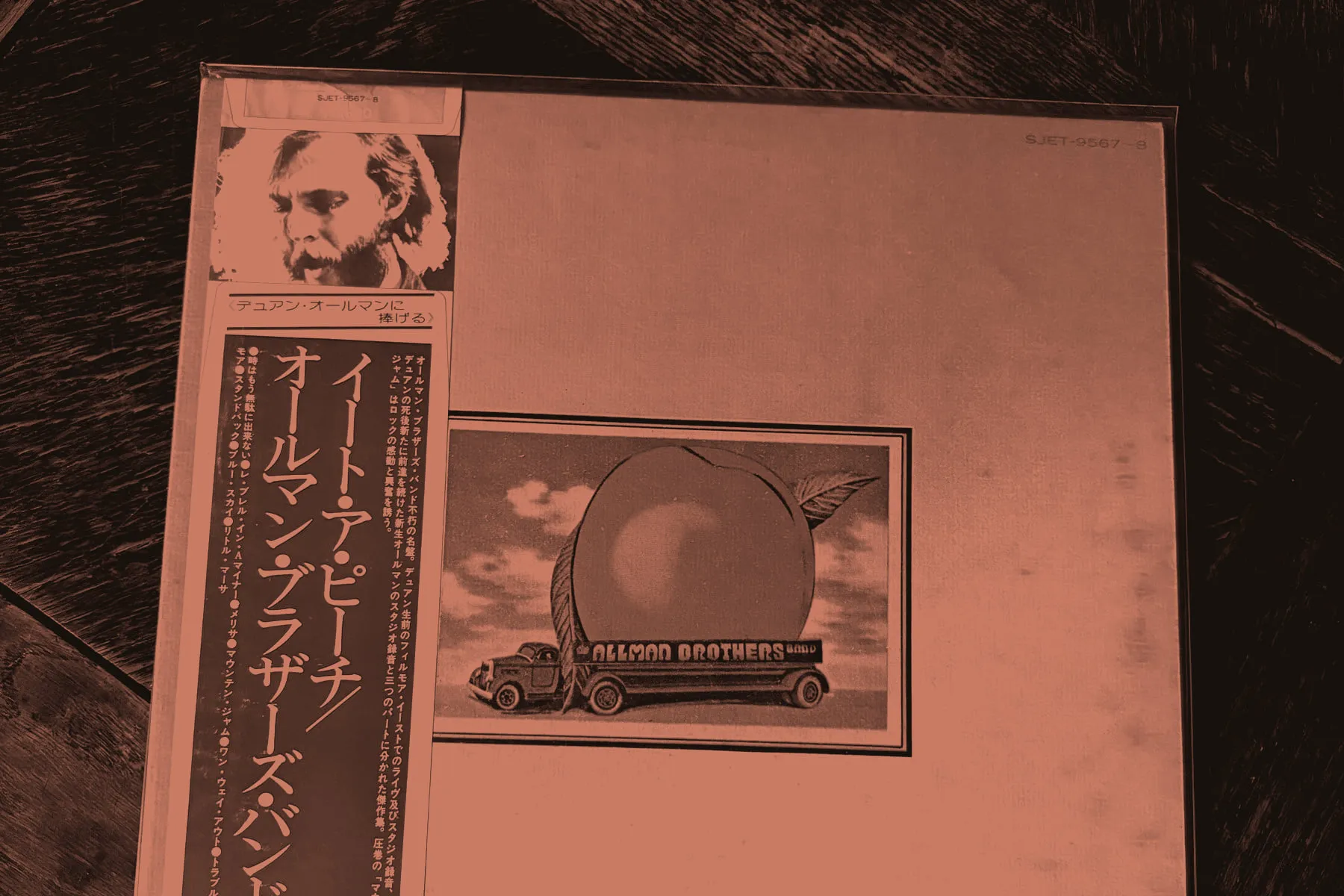 A Japanese LP of The Allman Brothers Band's Eat a Peach on a wooden table, with its obi wrapped around the left side of the sleeve.