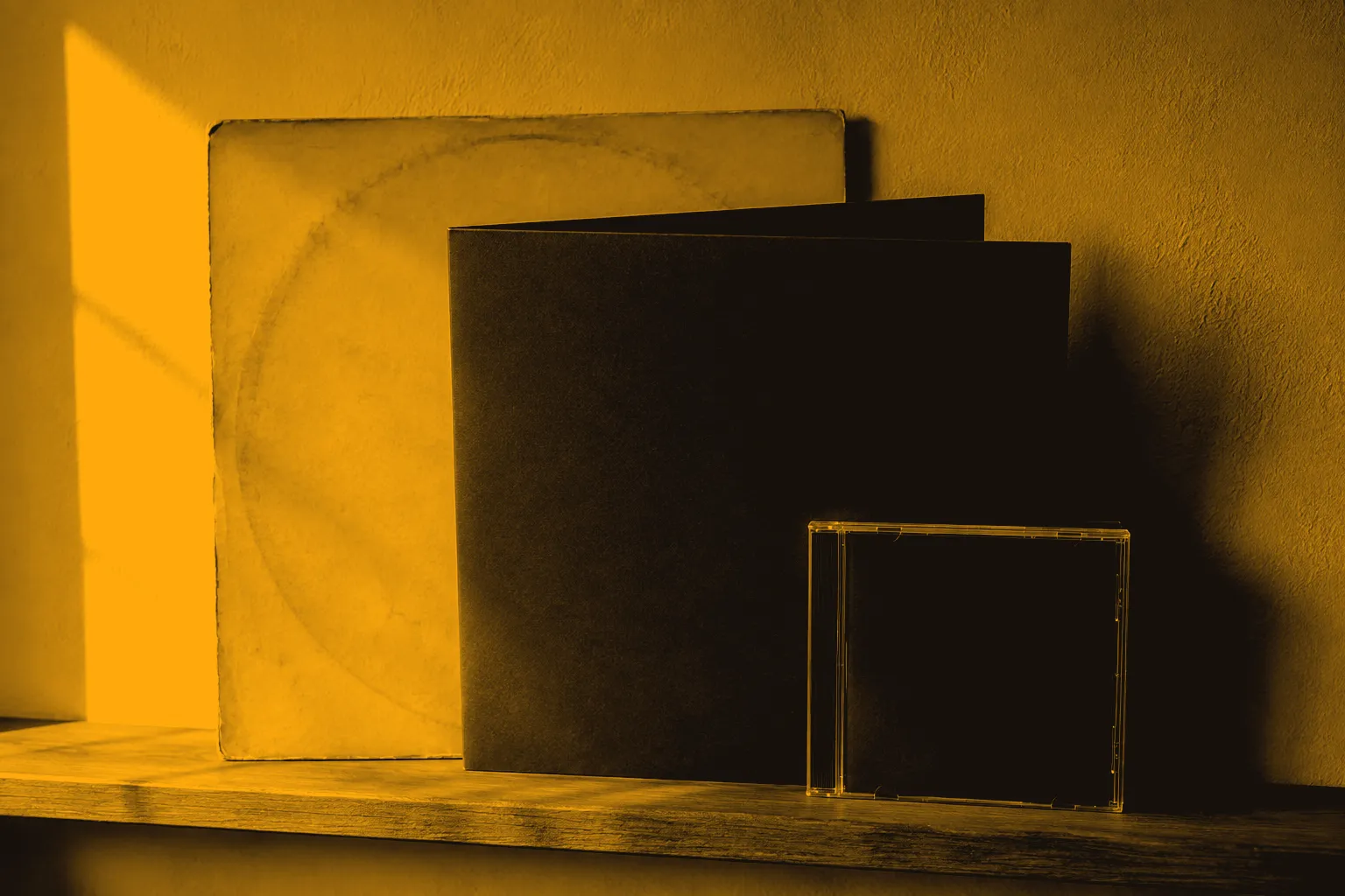 An aged record sleeve, a newer gatefold sleeve and a CD case on a ledge.