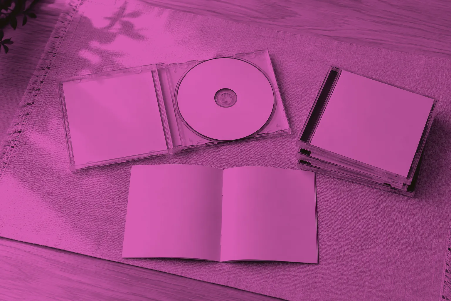 A CD case and paper booklet arranged on a linen-covered table.